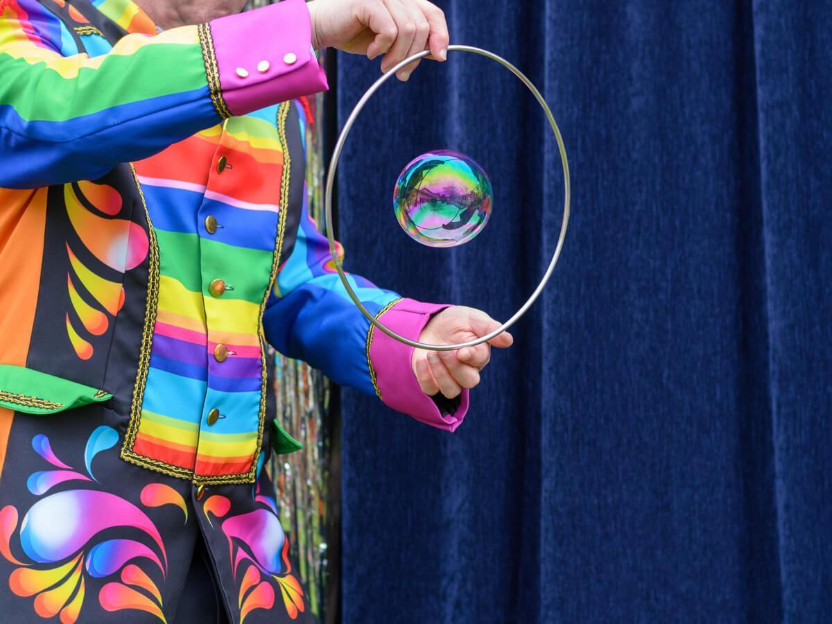 a person wearing a rainbow suit making bubbles