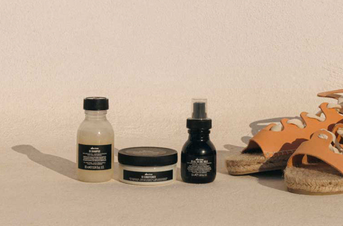 mini OI shampoo, OI milk, OI conditioner next to a pair of sandals