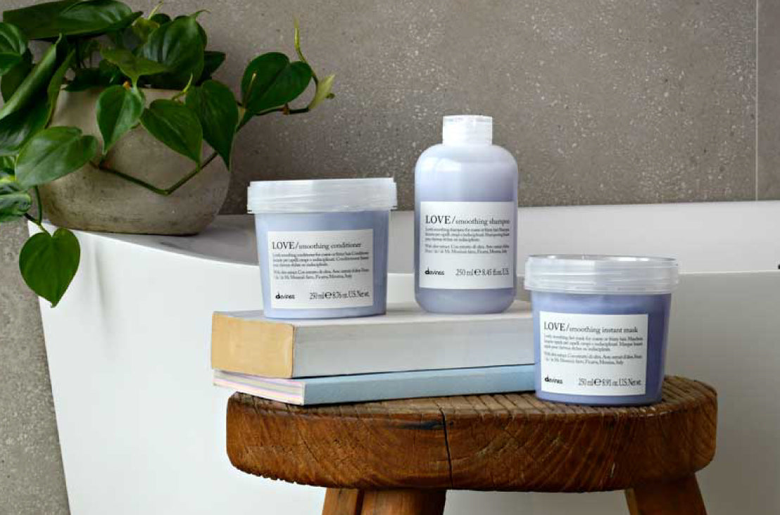Davines Love Smoothing Conditioner, shampoo, and instant mask sitting on a wooden stool with books